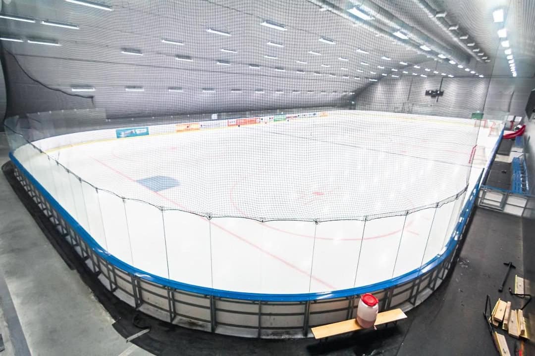 Montovaná ocelová oblouková hokejová hala Bruck – interiér s ledovou plochou, tribunou a moderním osvětlením, realizace HUPRO SYSTEMS SE.