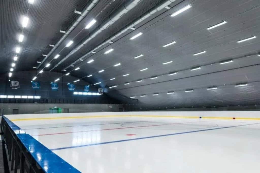 Montovaná ocelová oblouková hokejová hala Bruck – ledová plocha s mantinely a moderním osvětlením, čistý minimalistický interiér, realizace HUPRO SYSTEMS SE.