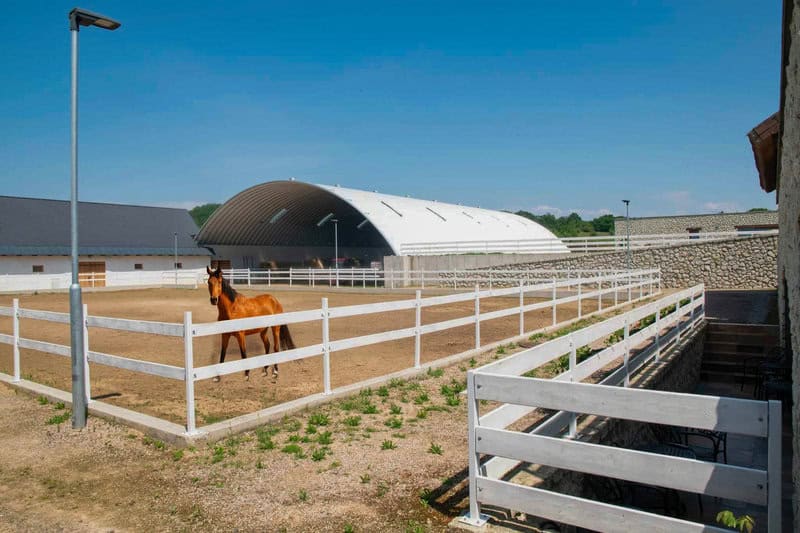 Montovaná ocelová oblouková jezdecká hala pro koně s venkovním výběhem a koněm v ohradě, moderní zemědělský areál, realizace HUPRO SYSTEMS SE.