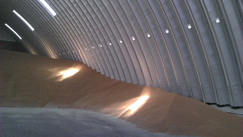 Interiér montované ocelové obloukové zemědělské haly s uloženým obilím ve velkém množství, realizace HUPRO SYSTEMS SE.