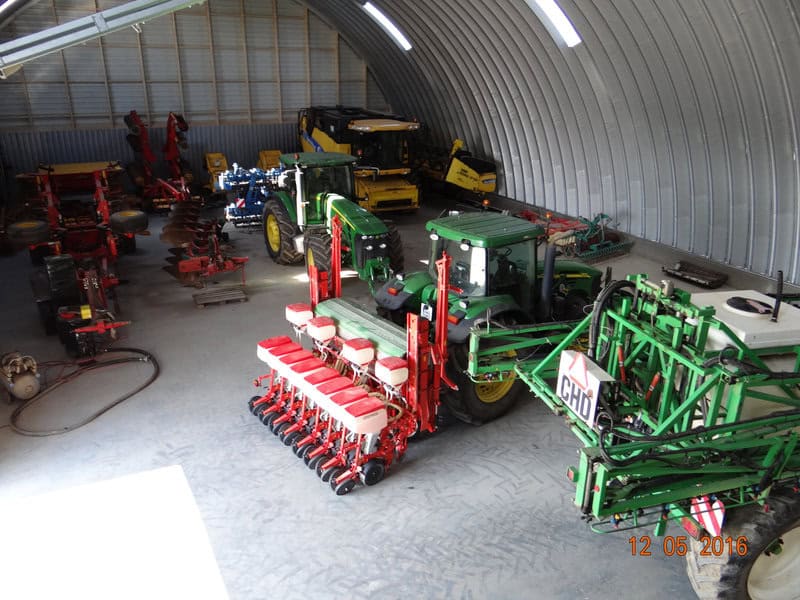 Ocelová oblouková montovaná zěmědělská hala plná zemědělské techniky – traktory, secí stroje a kombajn. Realizace HUPRO SYSTEMS SE.