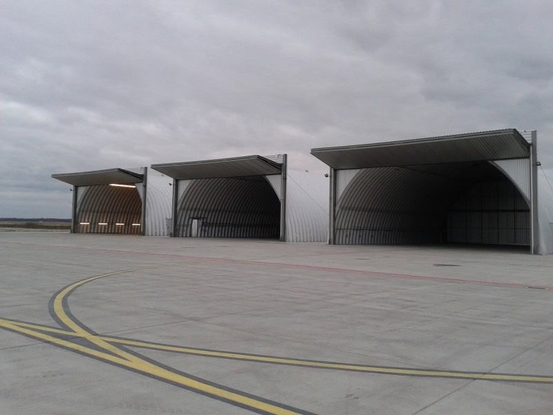 Obloukové ocelové montované armádní haly s otevřenými vraty na letecké základně, samonosná konstrukce HUPRO SYSTEMS SE