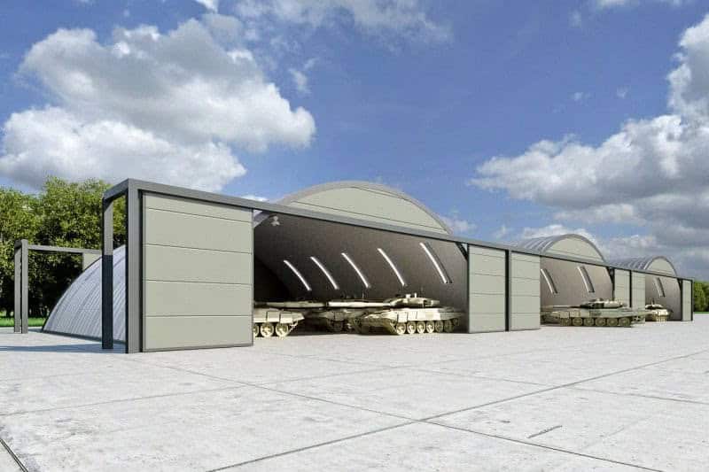 Obloukové ocelové montované armádní haly s tanky zaparkovanými uvnitř hangárů, samonosná konstrukce HUPRO SYSTEMS SE