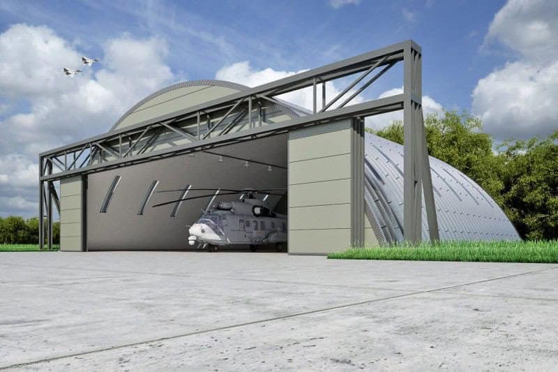 Oblouková ocelová montovaná armádní hala s vojenským vrtulníkem zaparkovaným uvnitř hangáru, samonosná konstrukce HUPRO SYSTEMS SE