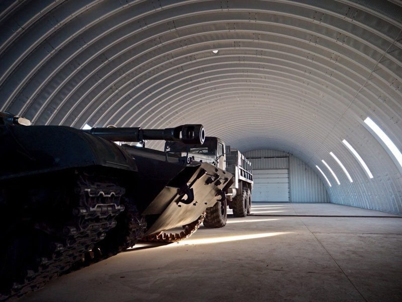 Oblouková ocelová montovaná armádní hala s vojenskou technikou, samonosná konstrukce HUPRO SYSTEMS SE