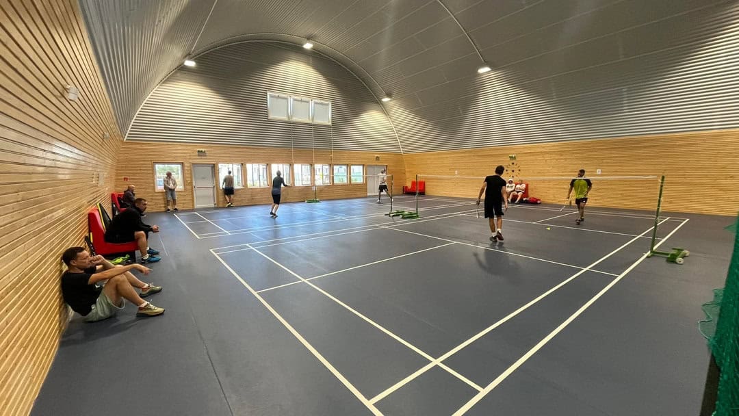 Interiér obloukové montované ocelové sportovní haly v Chorvátském Grobu s badmintonovými kurty, dřevěným obložením stěn a ocelovou konstrukcí systému HUPRO SYSTEMS SE.