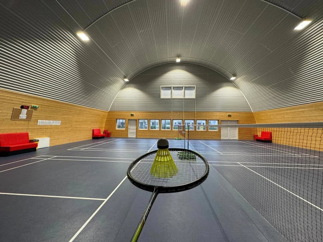 Badmintonový kurt v interiéru obloukové montované sportovní haly v Chorvátském Grobu s dřevěným obložením a ocelovou konstrukcí HUPRO SYSTEMS SE.