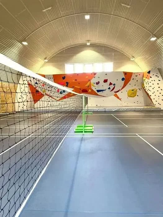 Interiér montované obloukové ocelové haly HUPRO v Chorvátskom Grobe s badmintonovými kurty a lezeckou stěnou, postavené systémem HUPRO SYSTEMS SE.