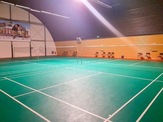 Interiér badmintonové haly v Paskově s moderní obloukovou konstrukcí, zeleným herním povrchem a několika badmintonovými kurty. Realizace HUPRO SYSTEMS SE.