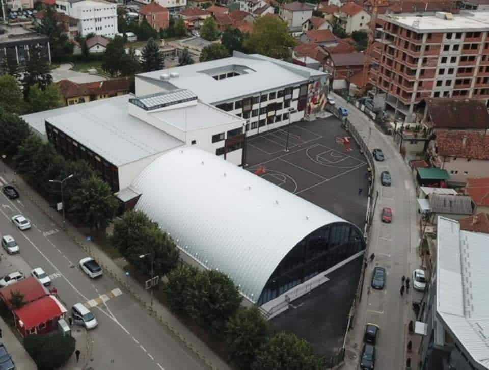 Montovaná ocelová plavecká hala Novi Pazar – letecký pohled na moderní krytý bazén s obloukovou střechou a přilehlým sportovním areálem, realizace HUPRO SYSTEMS SE.