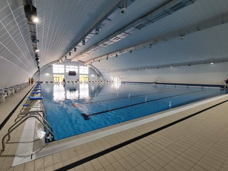 Montovaná ocelová plavecká hala Novi Pazar – interiér moderního krytého bazénu s plaveckými drahami a tribunou pro diváky, realizace HUPRO SYSTEMS SE.