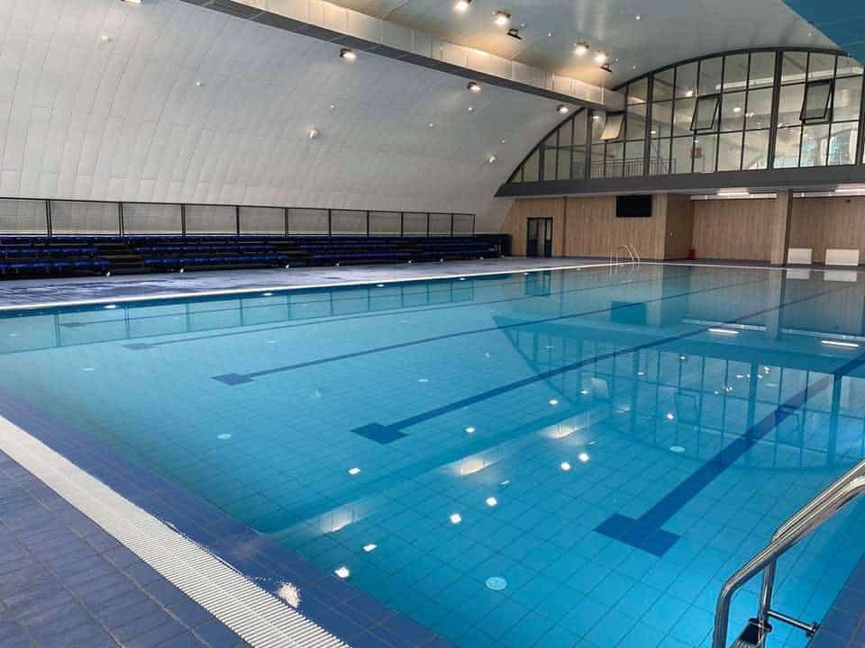Montovaná ocelová plavecká hala Novi Pazar – interiér krytého bazénu s tribunou pro diváky a prosklenou galerií v horní části objektu, realizace HUPRO SYSTEMS SE.