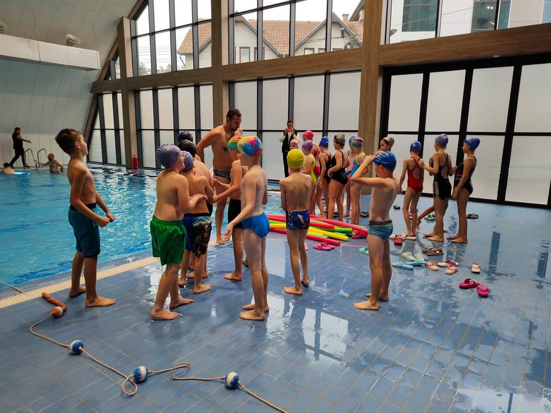 Montovaná ocelová plavecká hala Novi Pazar – interiér s výukou plavání pro děti vedenou instruktorem u krytého bazénu, realizace HUPRO SYSTEMS SE.