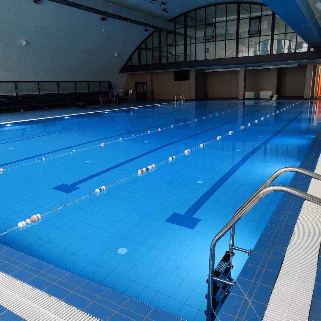 Montovaná ocelová plavecká hala Novi Pazar – interiér moderního bazénu s plaveckými drahami, tribunou a prosklenou galerií, realizace HUPRO SYSTEMS SE.