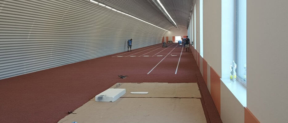 Sportovní hala v Prostějově s obloukovou ocelovou konstrukcí HUPRO SYSTEMS SE, určená pro atletiku, sprinty a tréninkové aktivity, s moderním zázemím a přilehlou venkovní plochou.