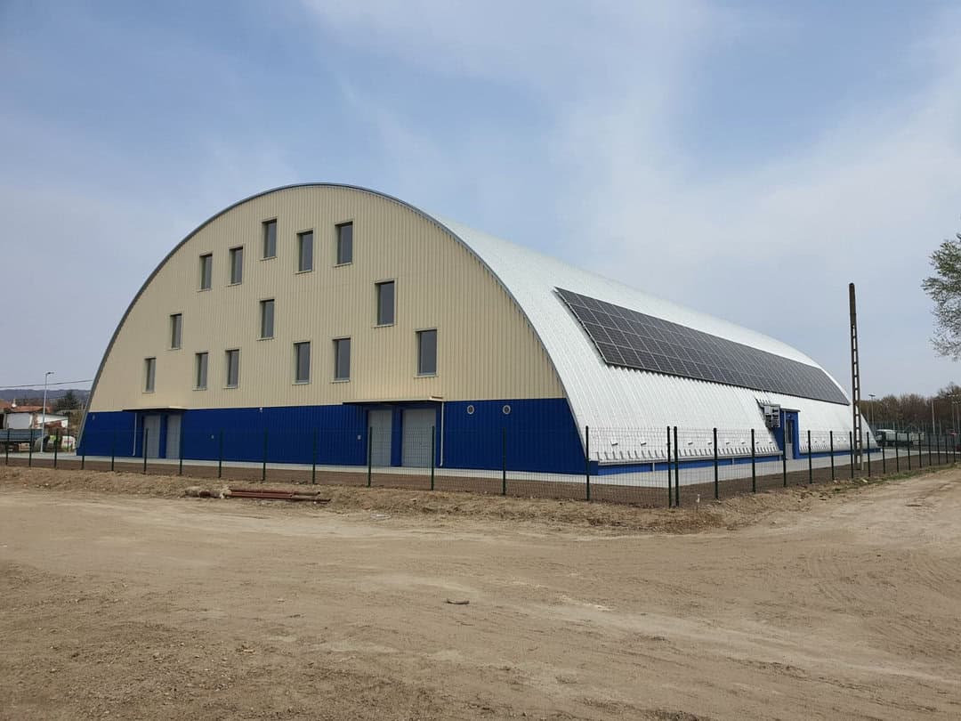 Montovaná ocelová sportovní hala Fót Phoenix Sportcsarnok, exteriér s fotovoltaickými panely na střeše, realizace HUPRO SYSTEMS SE.