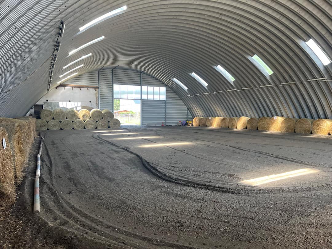 Jízdárna v Břeclavi s obloukovou ocelovou montovanou konstrukcí a balíky sena podél stěn, prosvětlená světlíky v klenbě. Realizace HUPRO SYSTEMS SE.