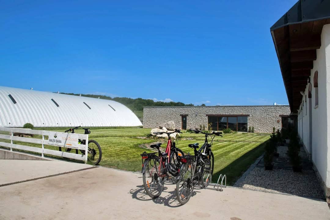 Areál jezdecké haly Majer Bara v Malé Bare s bílou obloukovou konstrukcí a travnatým nádvořím, postavený systémem HUPRO SYSTEMS SE.