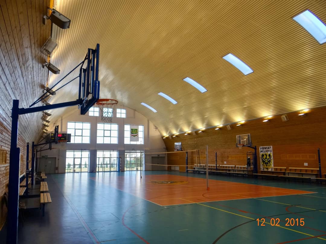 Montovaná ocelová oblouková víceúčelová sportovní hala Milicz, interiér s basketbalovými koši a volejbalovým hřištěm. Realizovala společnost HUPRO SYSTEMS SE.