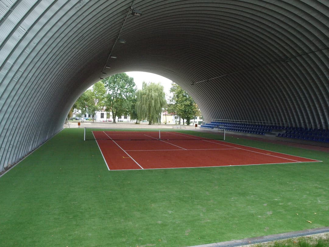 Montovaná ocelová oblouková tenisová hala Tomaszów Lubelski, interiér s krytým tenisovým kurtem. Realizovala společnost HUPRO SYSTEMS SE.