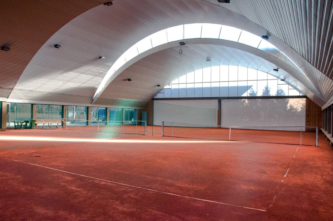 Interiér montované obloukové ocelové tenisové haly Varšava se dvěma antukovými kurty – realizovala společnost HUPRO SYSTEMS SE.
