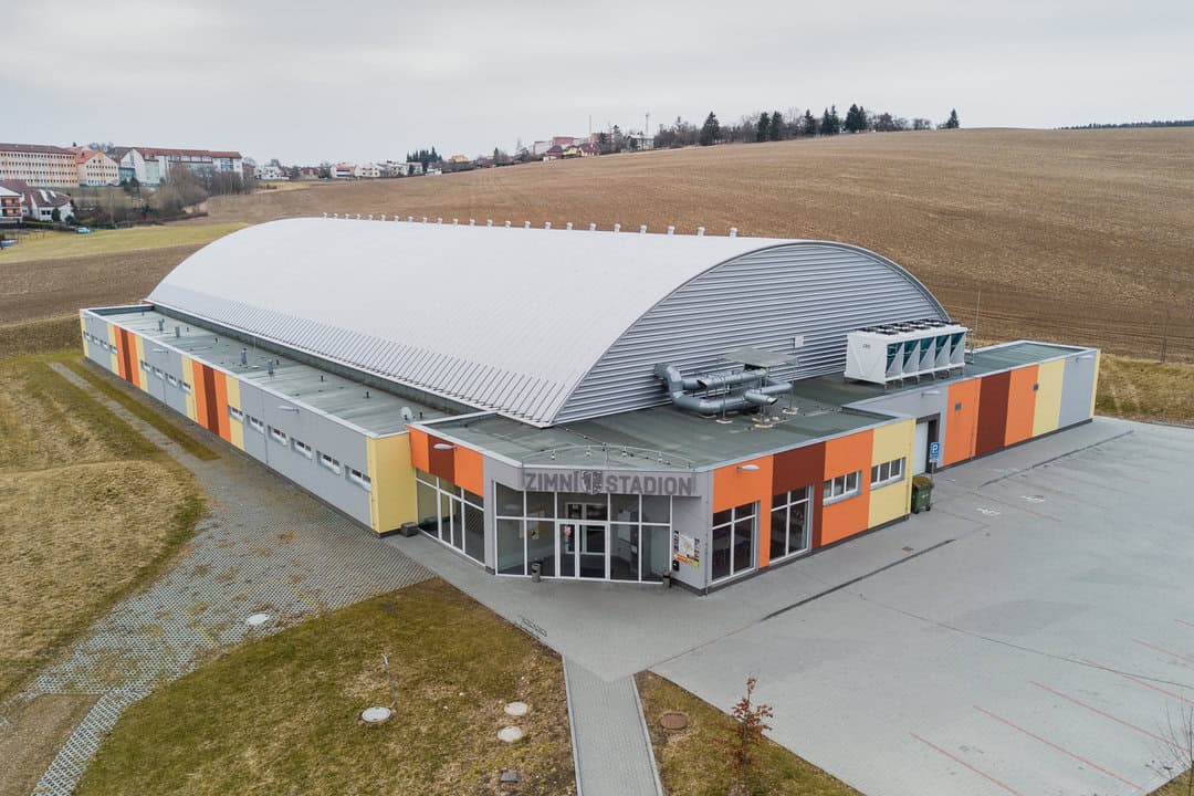 Zimní stadion v Bystřici nad Pernštejnem s obloukovou střechou a barevnou fasádou, realizace HUPRO SYSTEMS SE.
