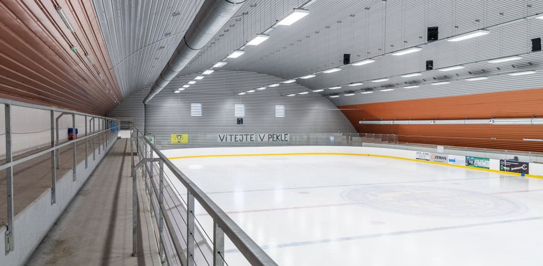 Ledová plocha zimního stadionu v Bystřici nad Pernštejnem s tribunou, nápisem „Vítejte v pekle“ a ocelovou obloukovou konstrukcí. Realizace HUPRO SYSTEMS SE.