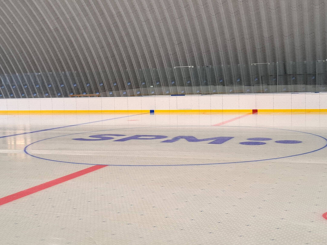 Interiér hokejové haly SPM Arena Praha s logem SPM uprostřed ledové plochy. Realizace HUPRO SYSTEMS SE.
