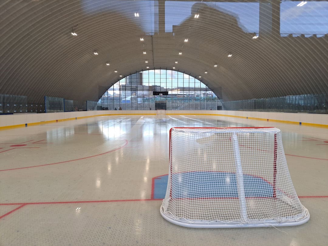 Interiér hokejové haly SPM Arena Praha s pohledem na branku a prosklené čelo haly. Realizace HUPRO SYSTEMS SE.