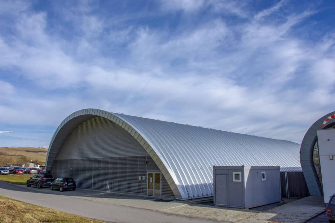Moderní oblouková montovaná ocelová sportovní hala v Tvrdošíně s hliníkovým opláštěním a technologií HUPRO SYSTEMS SE.