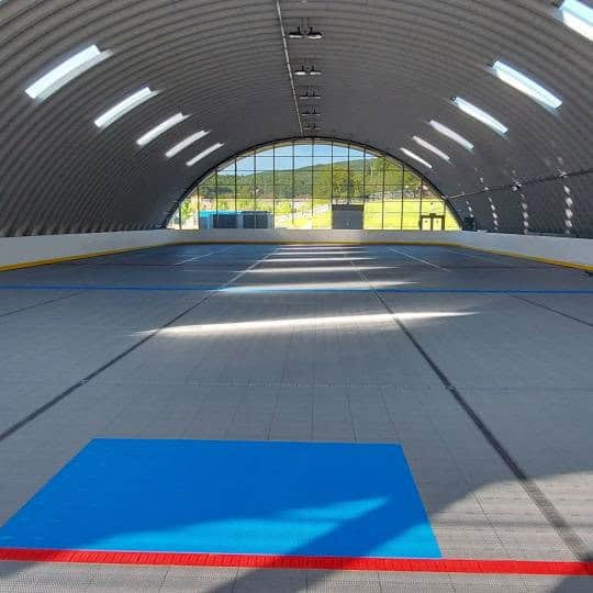 Interiér sportovní haly Javor v Tvrdošíně s multifunkční hrací plochou a proskleným čelním průčelím, moderní oblouková ocelová konstrukce postavená systémem HUPRO SYSTEMS SE.