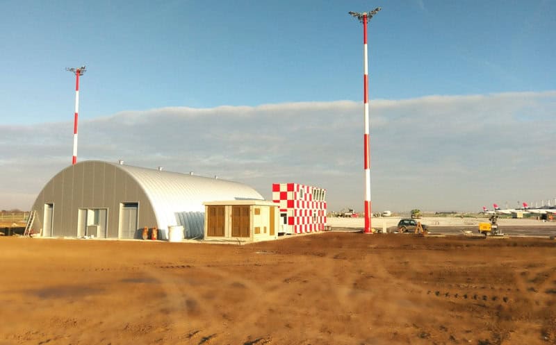 Oblouková ocelová montovaná letecká hala v areálu letiště určená pro technické a provozní zázemí, vyrobená z kvalitní oceli s vysokou odolností proti povětrnostním vlivům. Realizace HUPRO SYSTEMS SE.