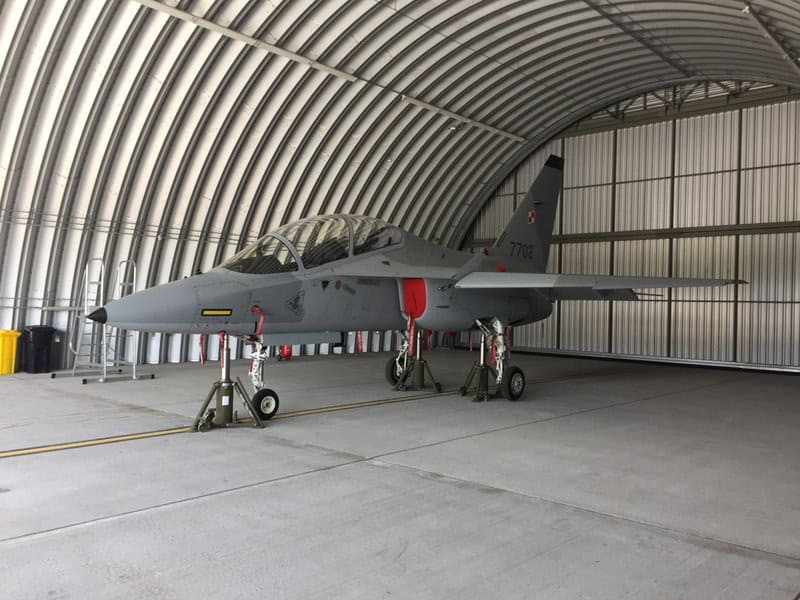 Oblouková ocelová montovaná armádní hala s vojenským letounem, určená pro servis a údržbu letecké techniky. Realizace HUPRO SYSTEMS SE.