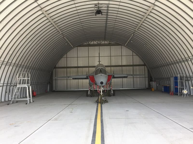 Oblouková ocelová montovaná letecká hala s vojenským letounem, určená pro údržbu a servis letecké techniky. Realizace HUPRO SYSTEMS SE.