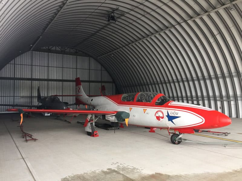 Oblouková ocelová montovaná letecká hala s vojenskými letouny, určená pro parkování a údržbu letadel. Realizace HUPRO SYSTEMS SE.