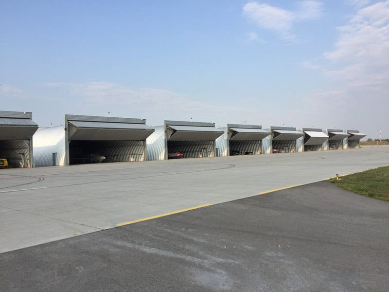 Obloukové ocelové montované letecké haly na letišti určené pro parkování, servis a údržbu letadel. Realizace HUPRO SYSTEMS SE.