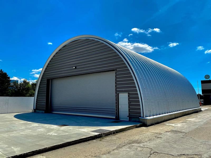 Oblouková ocelová montovaná letecká hala s rolovacími vraty a odolnou konstrukcí vhodná pro skladování a údržbu letadel. Realizace HUPRO SYSTEMS SE.