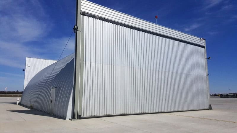 Oblouková ocelová montovaná letecká hala s uzavřenými vraty na letištní ploše, realizace HUPRO SYSTEMS SE