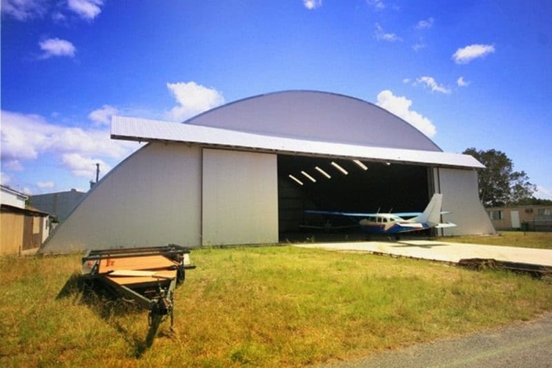 Oblouková ocelová montovaná letecká hala s malým letadlem zaparkovaným uvnitř, samonosná konstrukce HUPRO SYSTEMS SE