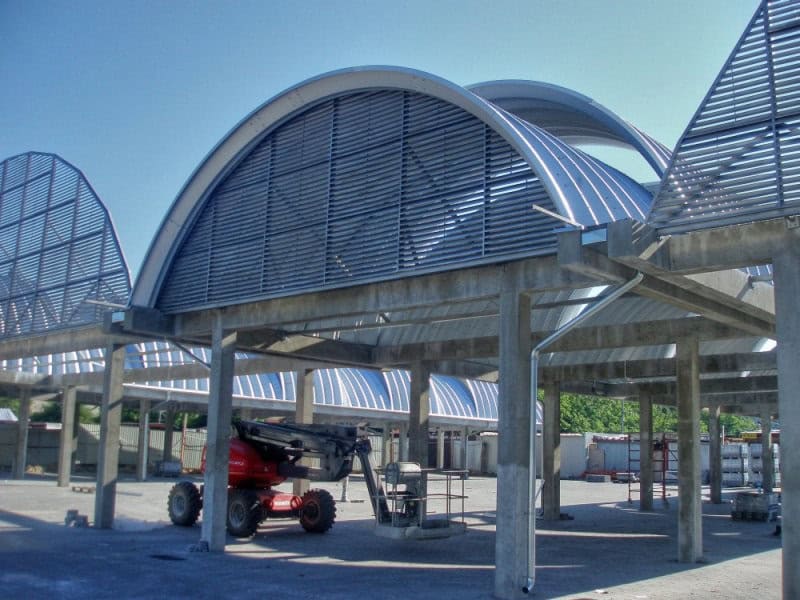 Ocelové montované obloukové haly HUPRO® s moderním designem a červenou střechou, vhodné pro průmyslové a komerční využití, realizace HUPRO SYSTEMS SE.