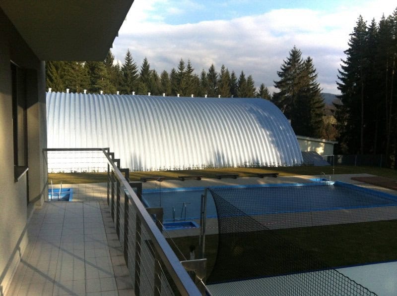 Oblouková ocelová hala na míru u bazénového areálu, pohled z terasy na konstrukci a sportovní zázemí, realizace HUPRO SYSTEMS SE