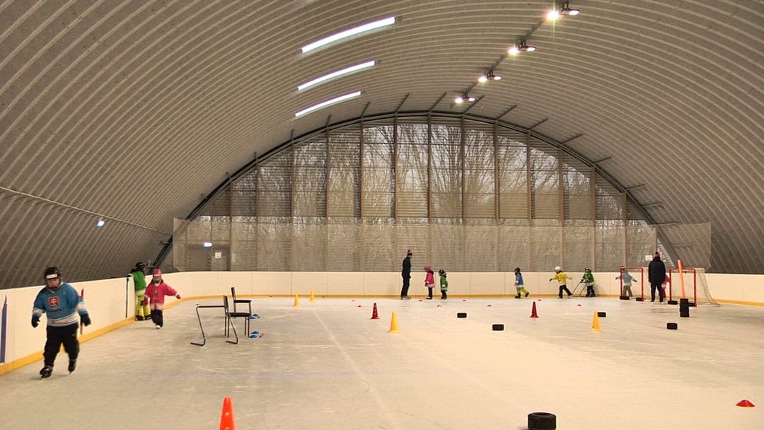Děti trénují bruslení v kryté sportovní hale ve městě Hurbanovo na Slovensku. Hala s ocelovou obloukovou konstrukcí slouží pro zimní sporty a hokejový trénink.