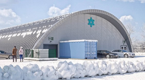 Zimní pohled na obloukovou montovanou ocelovou sportovní halu v Hurbanově na Slovensku. Hala se zasněženou střechou slouží jako krytá ledová plocha pro bruslení a hokej.