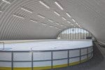 Interiér obloukové montované ocelové sportovní haly v Hurbanově na Slovensku s ledovou plochou pro hokej a bruslení. Moderní konstrukce s prosvětlením a energeticky úsporným provozem.