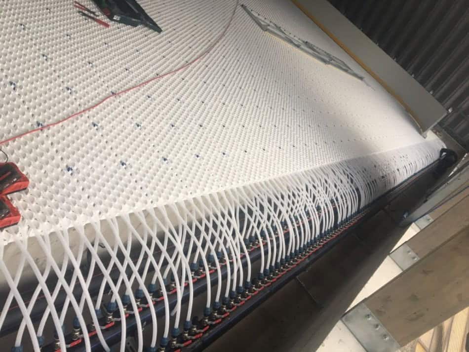 Detail montáže chladicího systému ledové plochy v obloukové montované ocelové sportovní hale v Hurbanově na Slovensku. Instalace potrubí pro rovnoměrné chlazení ledové vrstvy.