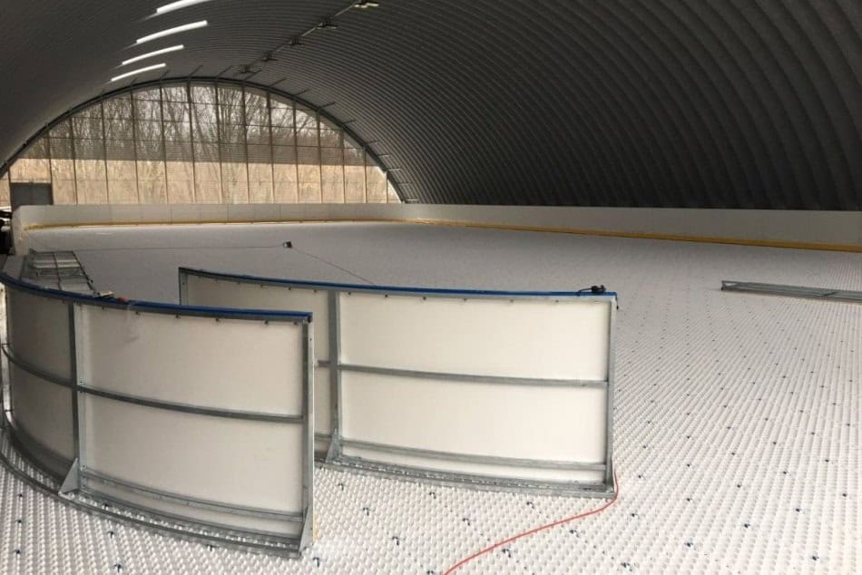 Montáž mantinelů a chladicího systému ledové plochy v nové obloukové montované ocelové sportovní hale v Hurbanově na Slovensku. Příprava zimního stadionu na provoz.