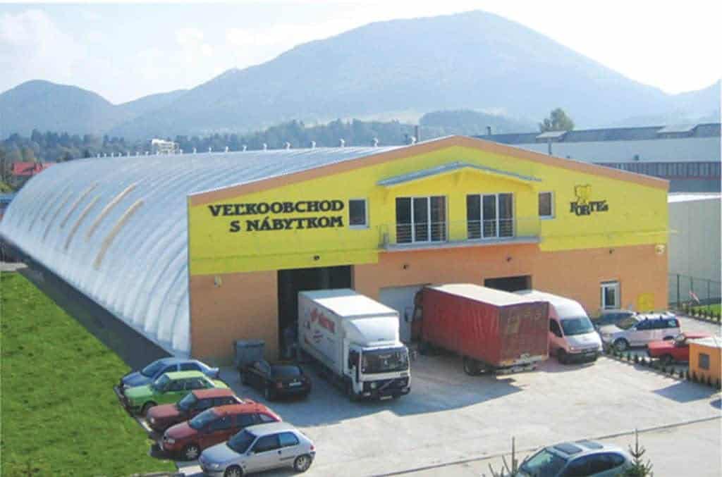 Montovaná ocelová oblouková hala využívaná jako velkoobchod s nábytkem ve městě obklopeném horami, realizace HUPRO SYSTEMS SE