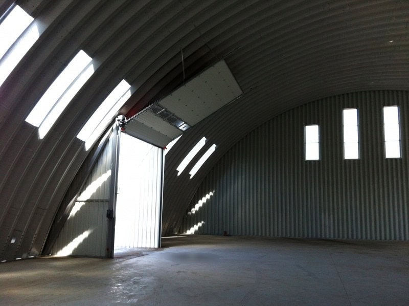 Interiér prázdné ocelové obloukové skladové haly s otevřenými vraty a denním světlem, realizace HUPRO SYSTEMS SE