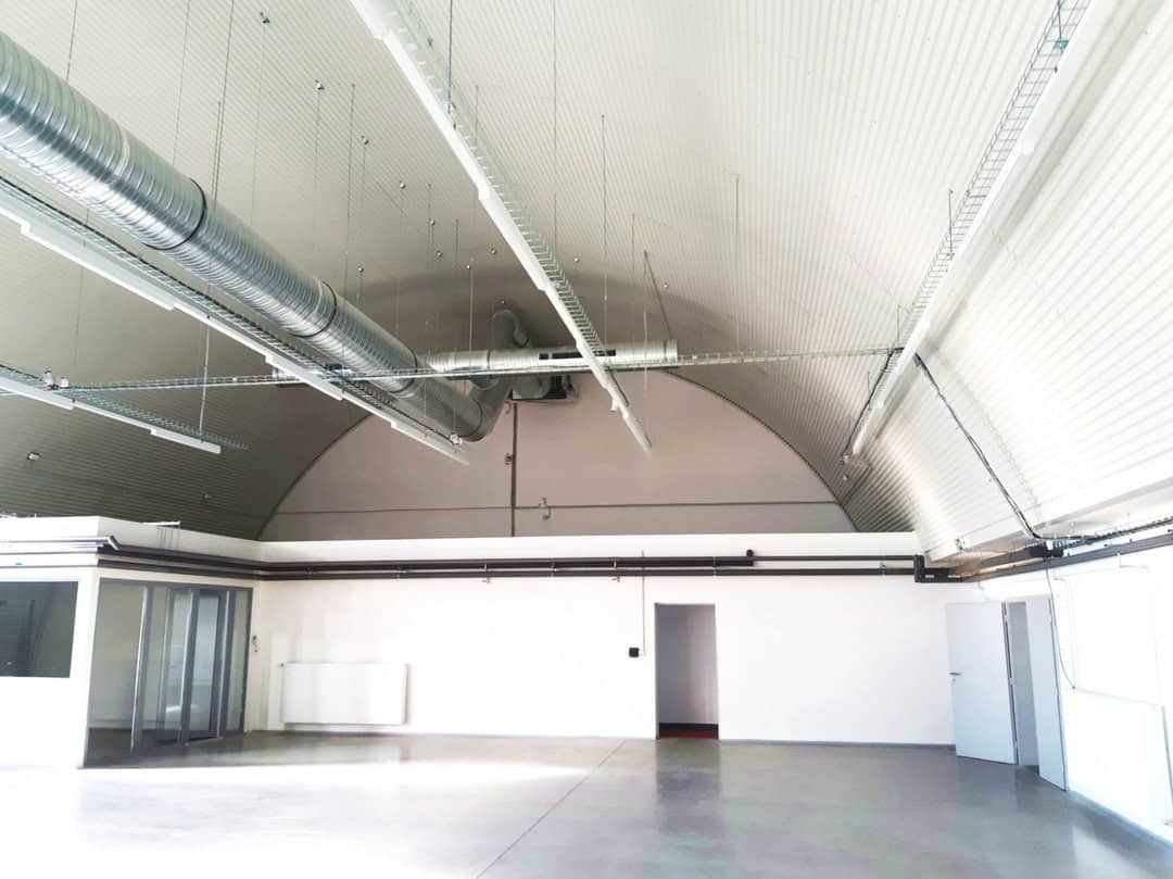 Interiér moderní skladové haly s obloukovou konstrukcí, ventilačním potrubím a zázemím, realizace HUPRO SYSTEMS SE
