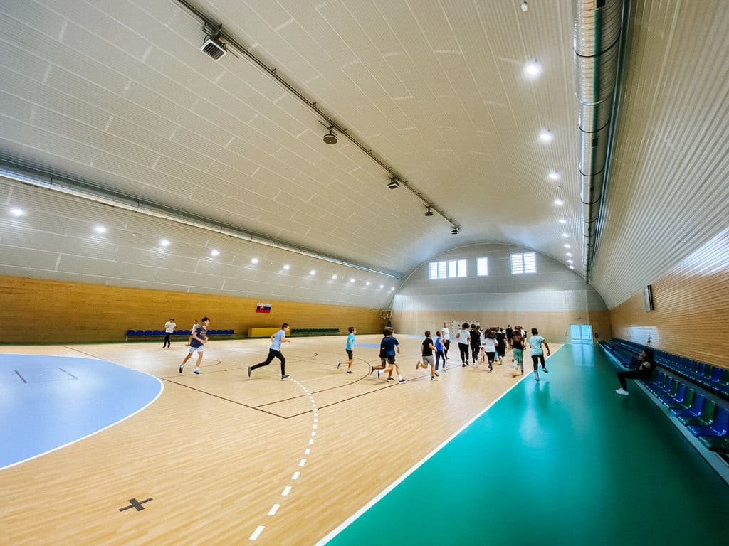 Studenti během hodiny tělesné výchovy v moderní sportovní hale ve městě Bytča na Slovensku. Halu s dřevěným obložením a víceúčelovým hřištěm realizovala společnost HUPRO SYSTEMS SE.